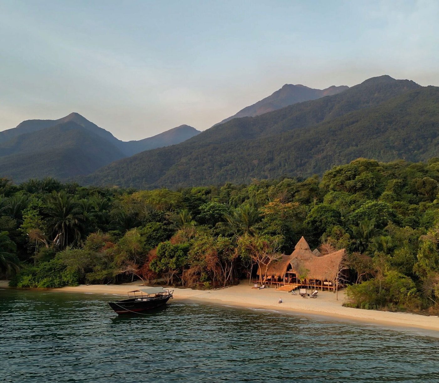 Greystoke Mahale's thatched camp sits on the beach below the mountains in Mahale