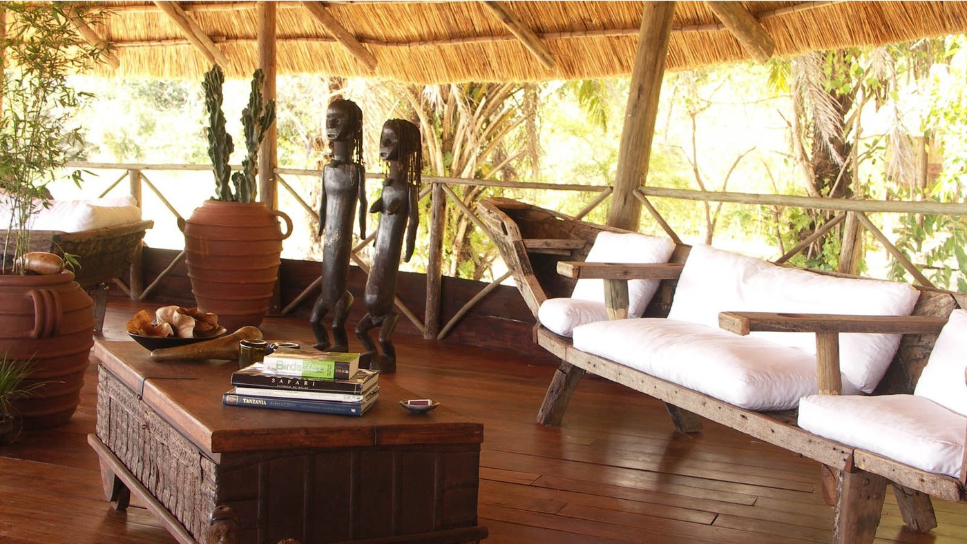 Carved figures and a daybed furnish the lounge at Nkungwe Beach Lodge