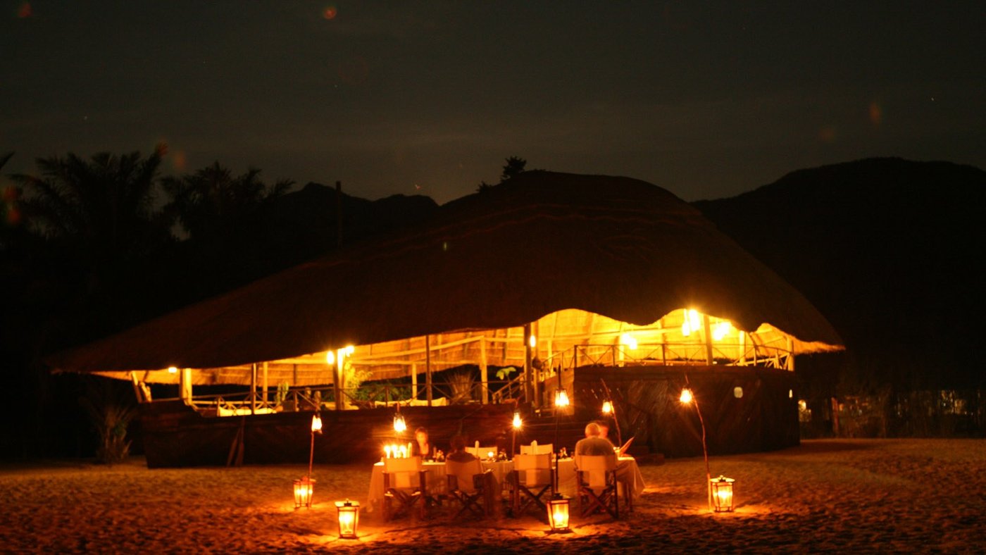 Candlelit dinner on the sand before the lit lodge at Nkungwe Beach Lodge