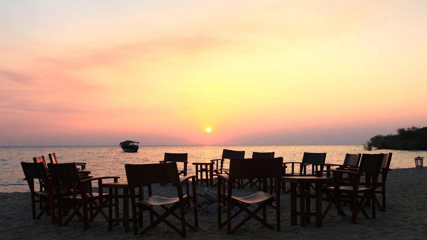 Chairs circle the beach at sunset over Lake Tanganyika near Nkungwe Beach Lodge